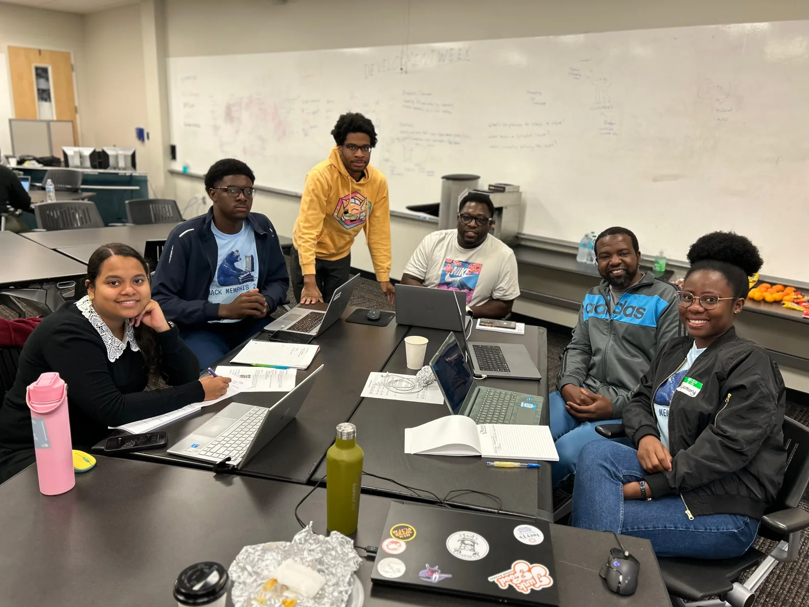 Participants working around a table of laptops at a hackathon build session in Memphis
